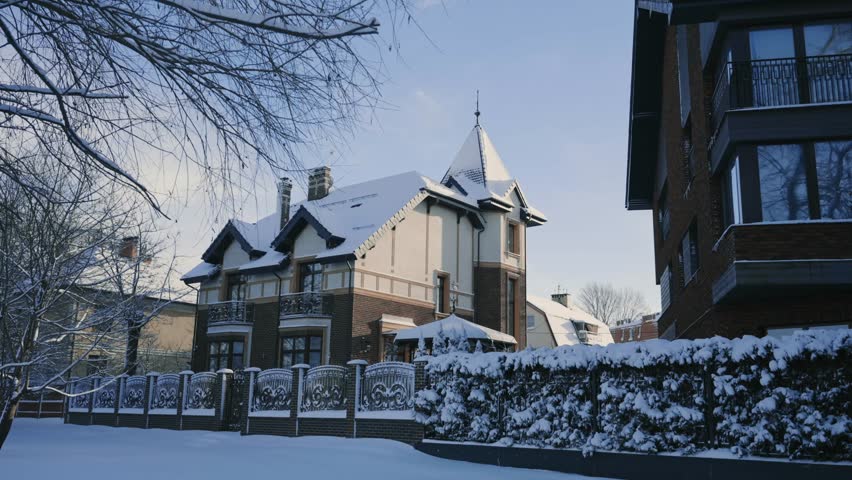 Snow covered residential house with ornate fence in winter