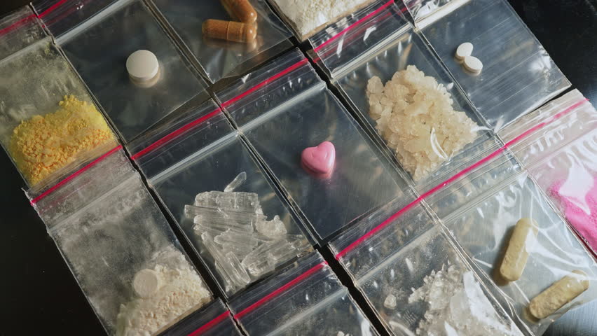 Pink heart shaped pressed pill ecstasy MDMA display, along with Fentanyl type opioid drugs in small packages, this drugs causing the most severe crisis in the world. Synthetic opioids Nitazenes.