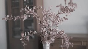 Minimalistic arrangement of pink dried eucalyptus branches in a white vase on a wooden table in cozy interior - Powered by Shutterstock - Get 15% off with code: PIKWIZARD15
