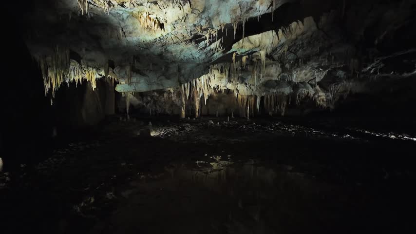 Exploring a cave with stunning rock formations and underground water in the dark