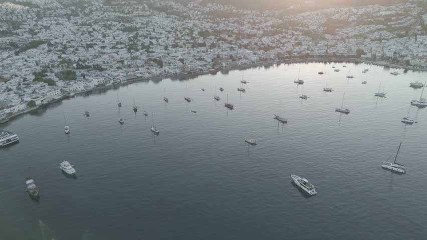 D-Log M. Bodrum, Turkey. Aerial drone shot of bay with stationary yachts, beachfront promenade and seaside houses in cool morning light. Aerial View