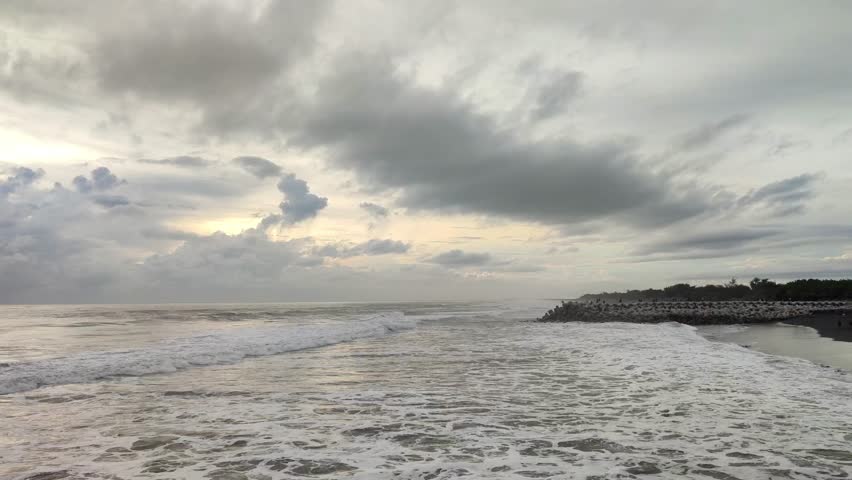 view of ocean waves under cloudy sky.
