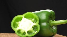 Rotating half and whole green bell pepper on wood black background. Fresh vitamin rich vegetable for cooking. - Powered by Shutterstock - Get 15% off with code: PIKWIZARD15