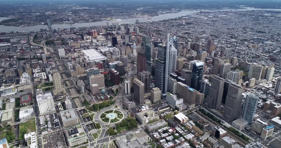 Philadelphia City Cityscape Skyscrapers and Delaware River Ben Franklin Bridge City Hall Logan Circle Park in Background. 4k. Drone POint of View. Aerial View Of A Modern Downtown City Skyline With Circular Park And River In Background