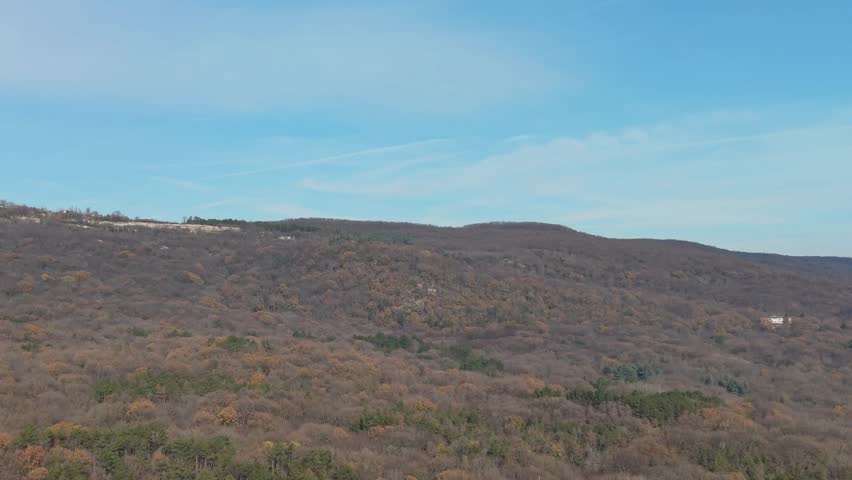 Aerial view of vast dry hills and open wilderness under clear blue sky, peaceful natural landscape, remote terrain, calm atmosphere