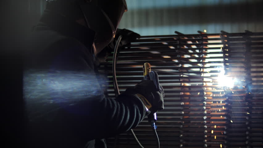 Welder welding steel rebar with arc sparks