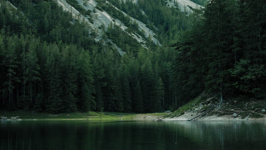 Peaceful cinematic landscape of Gruner See in Austria with still lake water reflecting lush alpine woodland