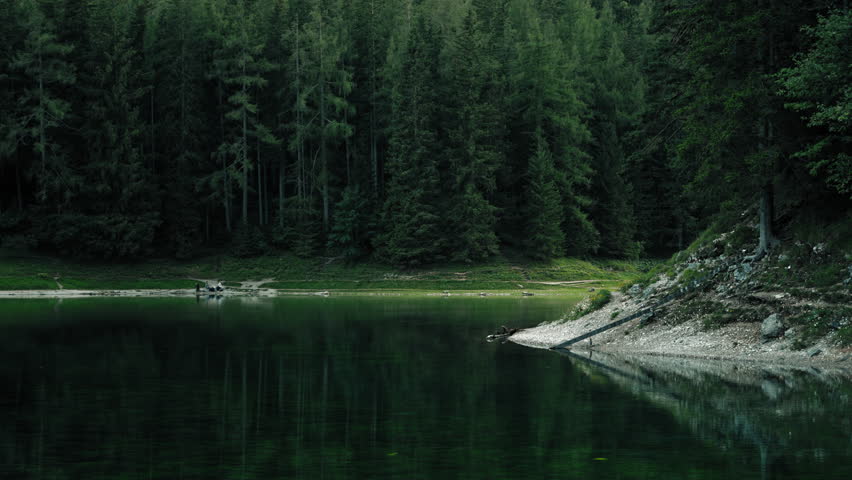 Peaceful cinematic landscape of Gruner See in Austria with still lake water reflecting lush alpine woodland