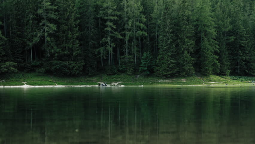Peaceful cinematic landscape of Gruner See in Austria with still lake water reflecting lush alpine woodland