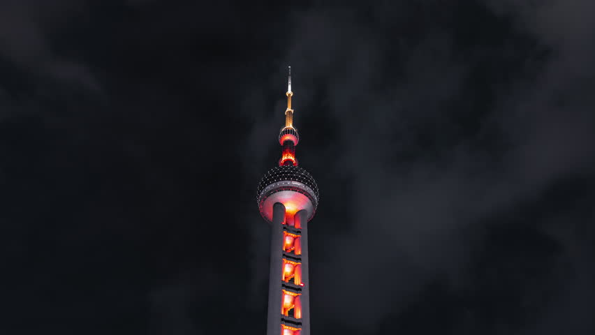 Dramatic night timelapse close-up of the Oriental Pearl Tower glowing red as clouds race across the dark Shanghai sky