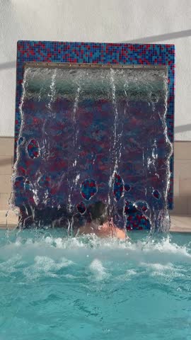 Boy in the pool under the waterfall