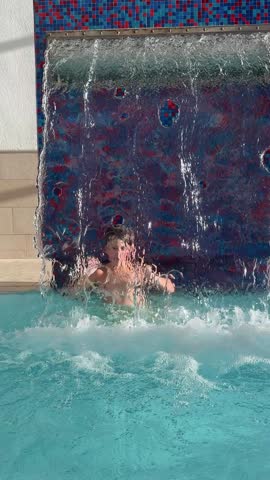Boy in the pool under the waterfall