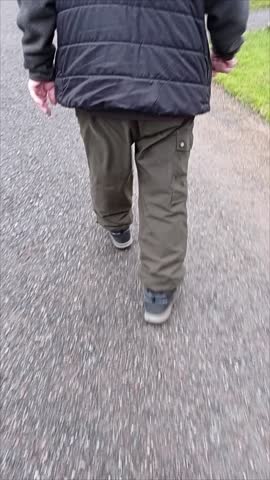 An elderly man with a puffer vest walking in a cemetery.