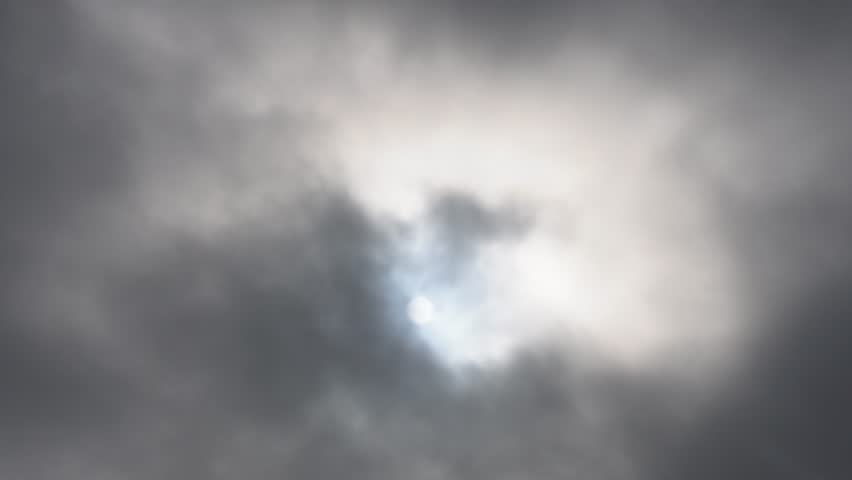 Dramatic sky featuring dark smokey grey clouds with sun rays breaking through