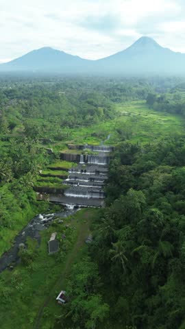 Majestic Mountain And Tiered Waterfalls Surrounded By Lush Green Jungle Landscape With Volcanic Peak In Distance