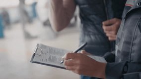 Handheld close-up of a female auto mechanic holding a clipboard and marking services rendered for a client’s car, ideal for automotive and business content. - Powered by Shutterstock - Get 15% off with code: PIKWIZARD15