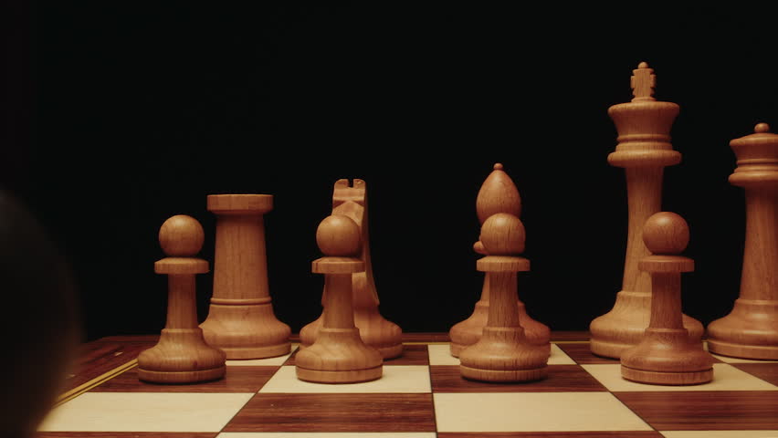 Close up and dolly zoom macro cinematic shot of wooden chess pieces on board. Black and light pawn, king, queen, bishop and rook stand. Strategic scene with chess on chessboard and dark background.
