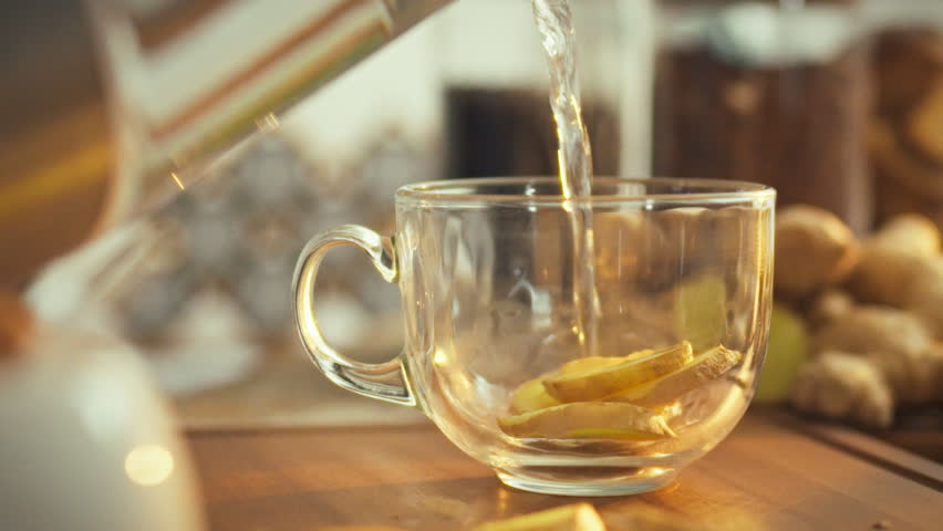 In a sunlit kitchen, chopped ginger rhizome infuses steaming hot water, releasing a pungent aroma rich in minerals and anti-inflammatory properties, highlighting the herb's healing benefits