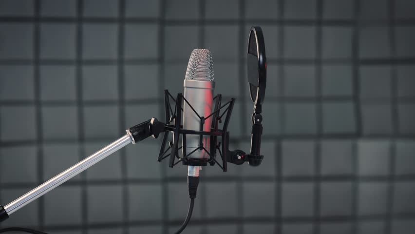 Recording concept. Tracking shot of professional vocal microphone and pop filter for singing or recording a podcast in a bedroom music studio SLIDE RIGHT