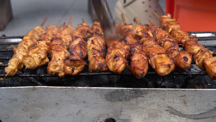 grilling chicken satay on charcoal grill footage video. traditional food of indonesia, sate madura. grilling chicken satay skewers close up video. the process of grilling chicken sate