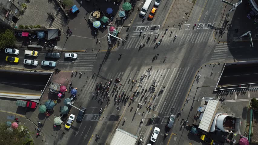 Top view of the vehicular and pedestrian flow at the intersection of Calzada Independencia and Avenida Juárez. Pedestrians cross the street while vehicles turn around. Guadalajara, México - December 31, 2025