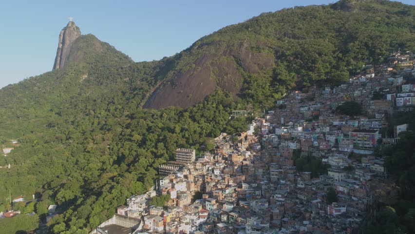 Wide aerial of hillside favela beneath Christ the Redeemer in Rio de Janeiro, Brazil