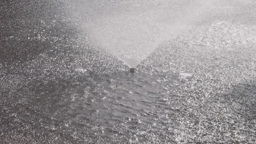 Close up view of splashing fountain in pond in sunny day, 4k slow motion footage b roll shot, backlit effect.