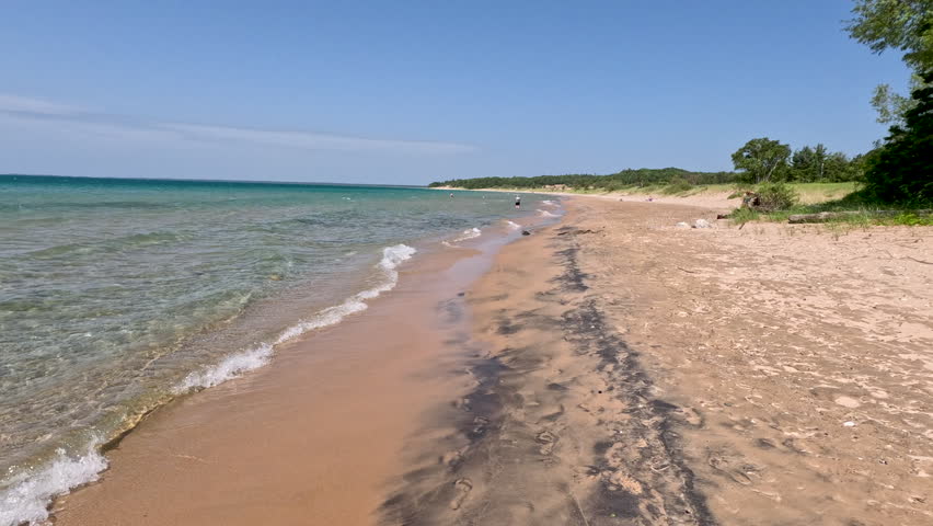 Unspoiled Nature Scene on the Beaches of Lake Michigan. Reverse motion walking on the beautiful beaches of Lake Michigan. Pure, clear transparent waves roll onto the shore. Unspoiled nature located within Wilderness State Park in Northern Michigan, USA. 