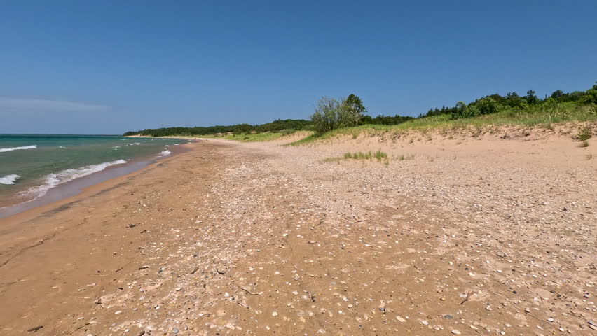 Unspoiled Nature Scene on the Beaches of Lake Michigan. Moving across the the sandy beach of Lake Michigan. Big waves roll onto the shore. Sand dunes and forest line the beach. Unspoiled nature located within Wilderness State Park in Northern Michigan, USA.