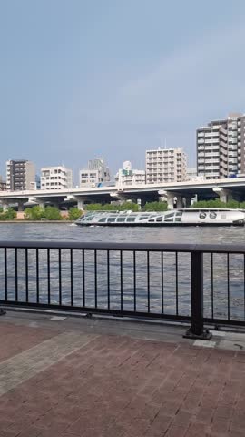 A sleek, futuristic water bus navigates the Sumida River in Tokyo, Japan, featuring the iconic Tokyo Skytree and urban cityscape under a clear blue sky. Perfect for travel and urban lifestyle themes