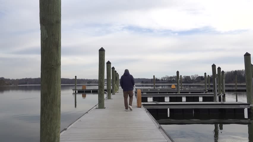 Leonardtown, Maryland USA A man walks on a public boat pier in the Leonardtown Wharf Park on the Potomac River in winter. 