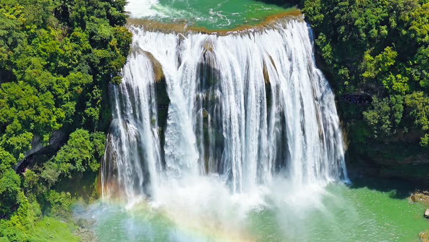 The famous Huangguoshu Waterfall natural landscape in Guizhou, China. Aerial shot of a magnificent large waterfall cascading down into a turquoise pool surrounded by lush green tropical forest in summer.