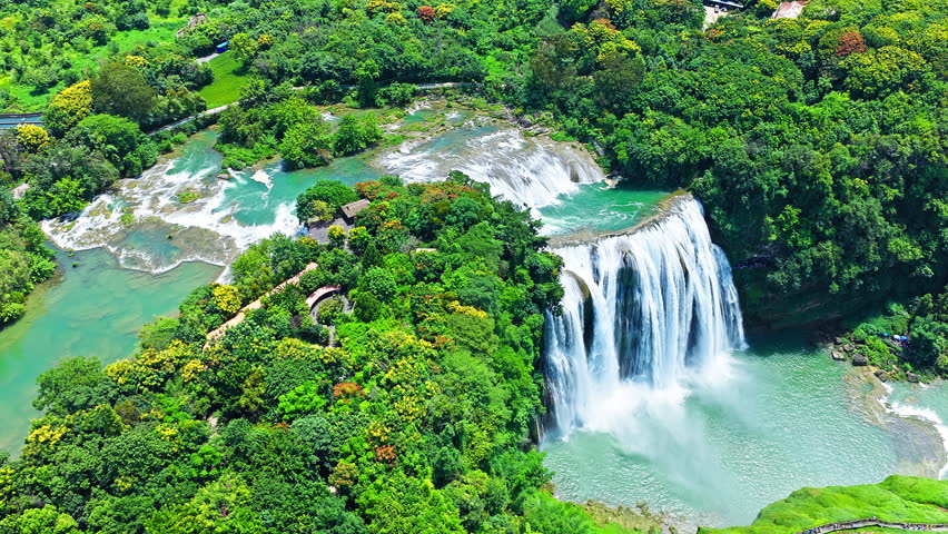 The famous Huangguoshu Waterfall natural landscape in Guizhou, China. Aerial shot of a majestic waterfall cascading into a green lake surrounded by lush forest in summer.