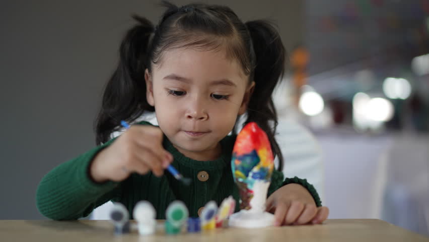 child girl painting plaster statue on the table