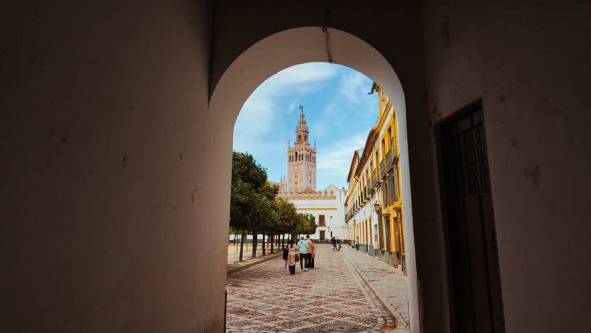Patio de Banderas, a large courtyard adjacent to the Royal Alcazar of Seville, Spain with the Giralda bell tower in the background
