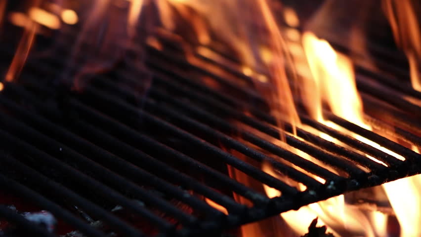 Burning wood logs in a barbecue grill with fire flames, intense heat and bright sparks