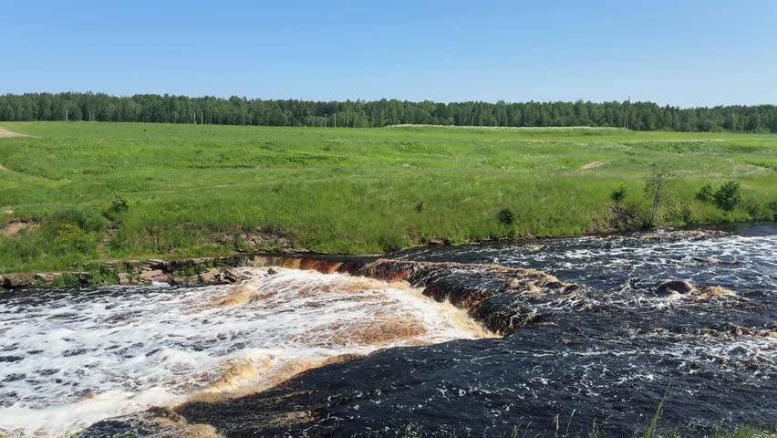 A wide, rushing waterfall with small cascade, creating foam, capturing the raw power of nature.