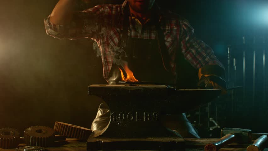 Cinematic close-up of blacksmith forging glowing hot iron on anvil with sparks flying. Shot in dramatic lighting on dark background with high-speed camera at 1000fps. Camera in motion. Speed Ramp.