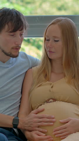 Caring husband supports his pregnant wife as they practice breathing exercises together to ease tension during early labor contractions and prepare for childbirth. Slowmotion video.