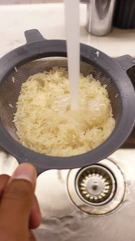 Rinsing rice in preparation for cooking at kitchen sink
