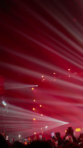 Powerful laser beams crossing above dense concert crowd during performance