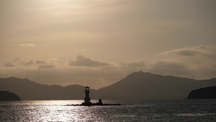 a silhouette scene of small lighthouse in the sea in sunset