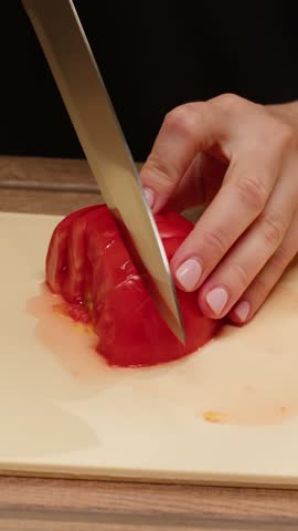 Chef woman slicing tomato using knife on the table in home. Process of cutting and preparation food in kitchen.