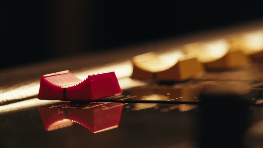 Music studio close up, Close up hands shot of sound engineer using mixing console, remote control for adjusting sound, audio mixer. Musician creates music, makes remix for DJ set. Sound recording