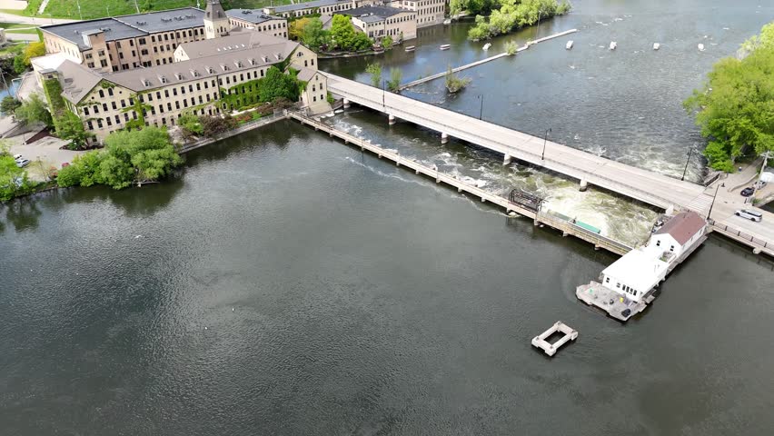 Slow push Drone shot over Fox River Bridge and Historic Brick Buildings.  Near Downtown Appleton Wisconsin USA.  One car drivingon bridge while Rushing water below from Hydro Electric Dam.