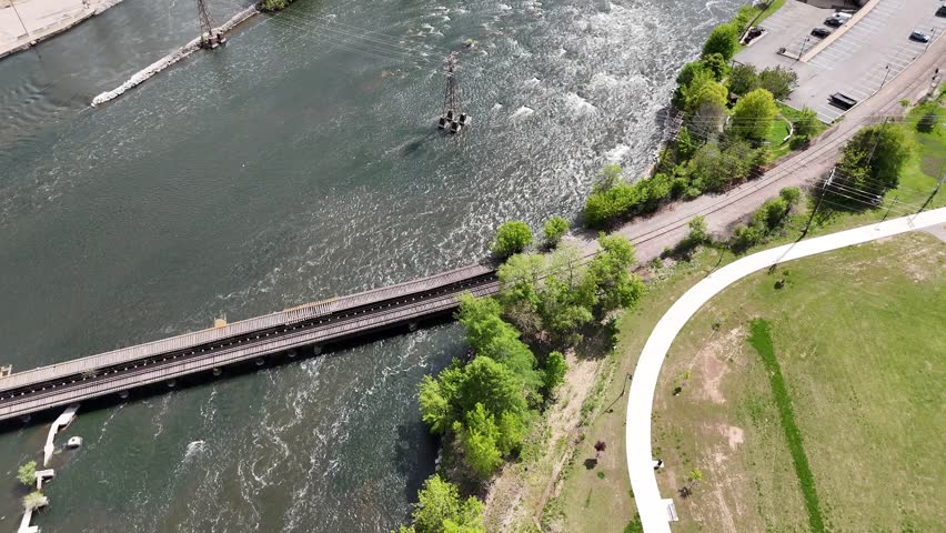 Birdseye Drone shot of Fox River Dam and Hydro Electric Plant in Appleton Wisconsin USA.  Rushing water and rapids.  Road and Building next to river. Sunny Summer Day.