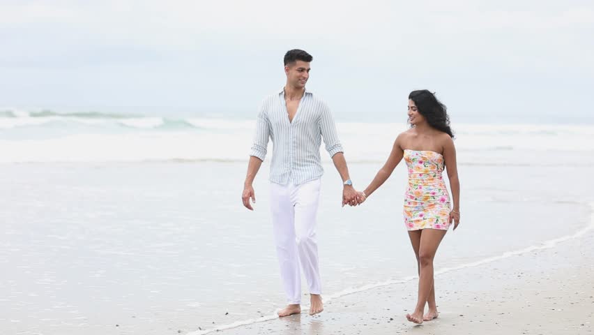 Romantic young couple walking hand in hand on the beach