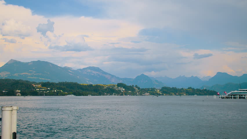 Wooden pier extending into Lake Lucerne with mountains and calm water in the background.