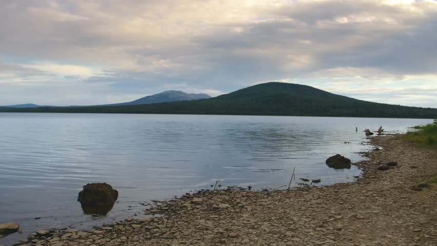 summer water landscape showing the shore of high-mountain Lake Zyuratkul and the surrounding mountain range within Zyuratkul National Park, Chelyabinsk region, Russia.