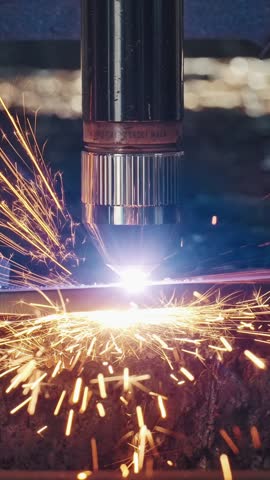 Industrial CNC laser cutting machine processing metal sheet with bright sparks and plasma light. High precision manufacturing technology in modern metalworking industry